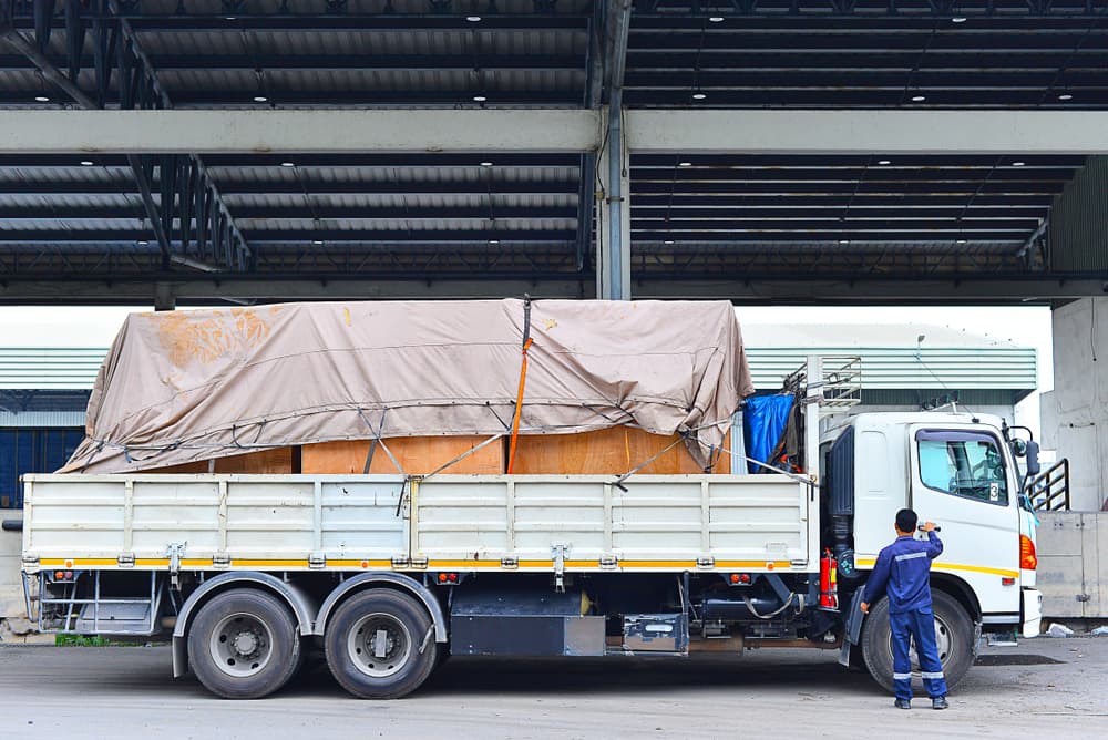 A logistics truck with a canvas cover and a wooden box.






