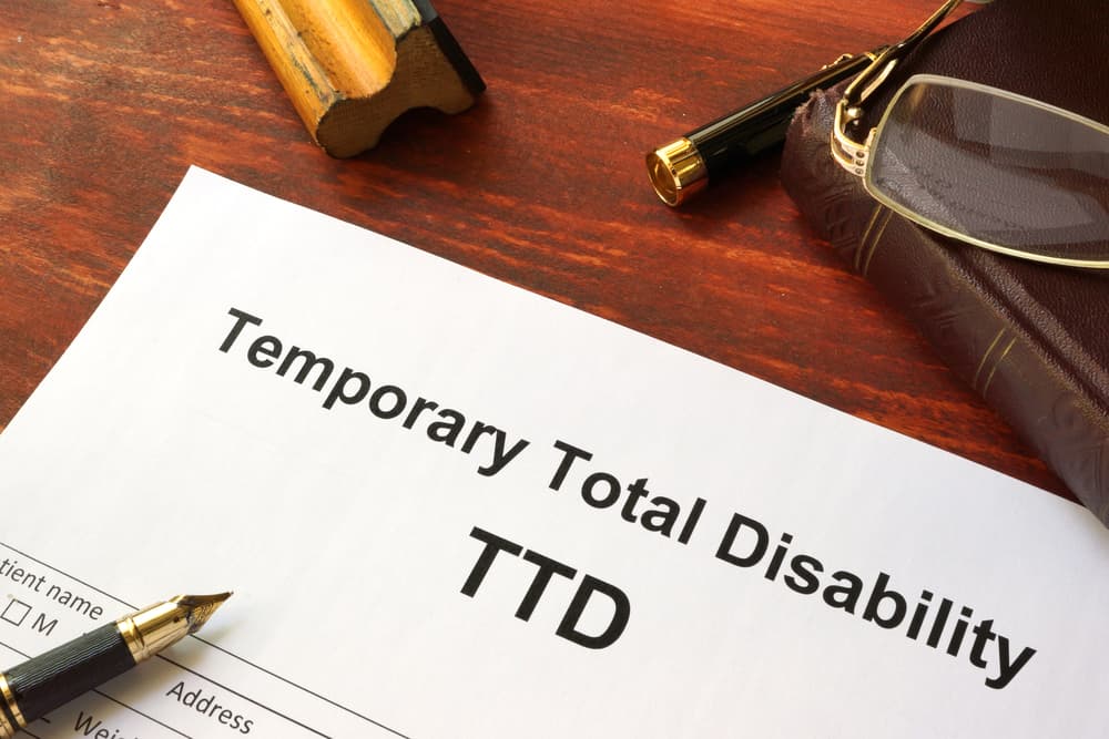 Temporary Total Disability (TTD) form on a wooden table.