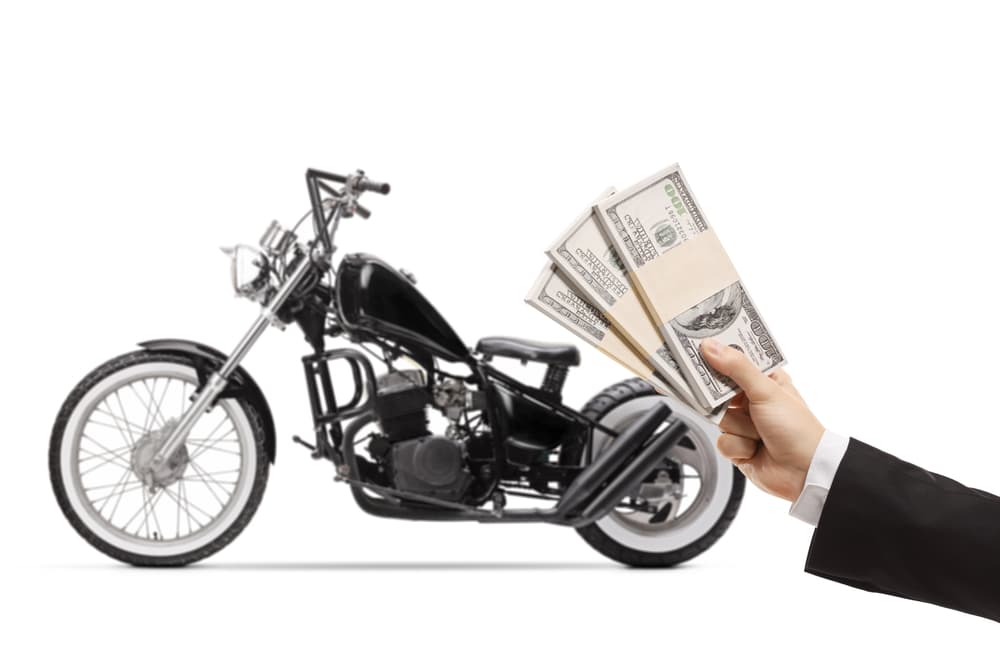 Money in the hand of a man & motorcycle in background 