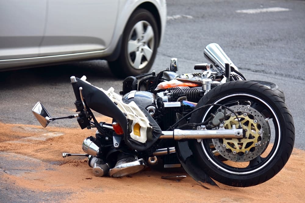 Damaged motorcycle on the road after collision with a car